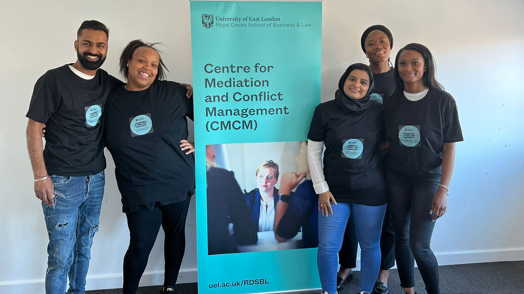 Centre for Mediation interns smiling in front of pull up banner