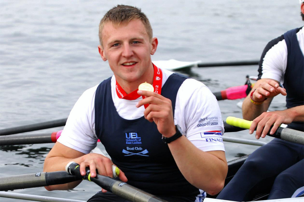 Rower John Collins holding his medal,