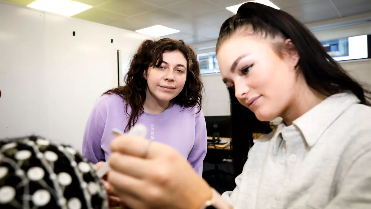 A student and a teacher putting electrodes on a man's head