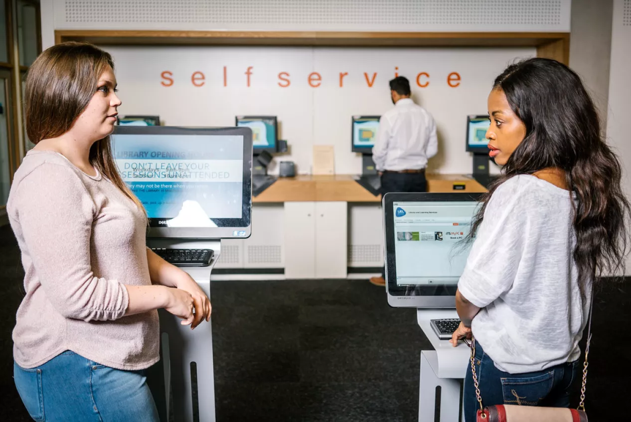 Two students in Stratford Library standing in front of computers