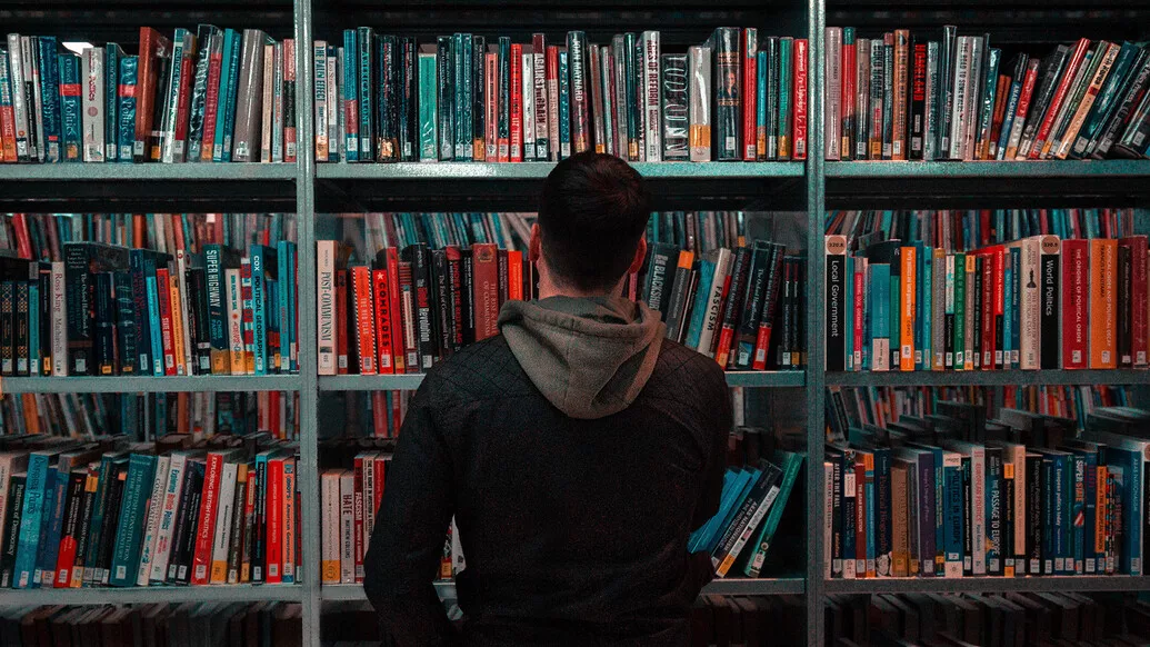 Male student standing in front of books in the library