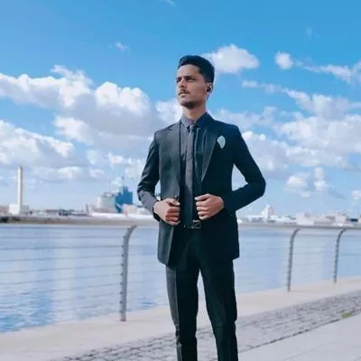  a man in a suit and tie standing by the water. 