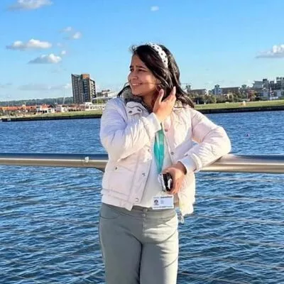  a woman talking on a cell phone next to a body of water. 