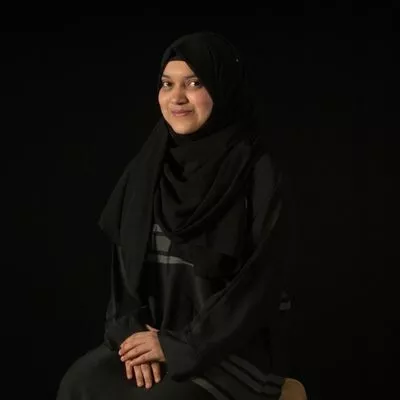  a woman in a black hijab sitting on a chair. 