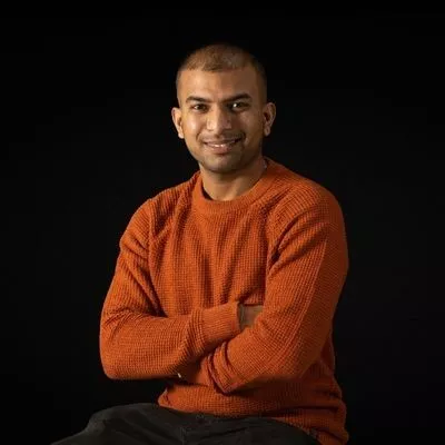  a man in an orange sweater posing for a picture. 